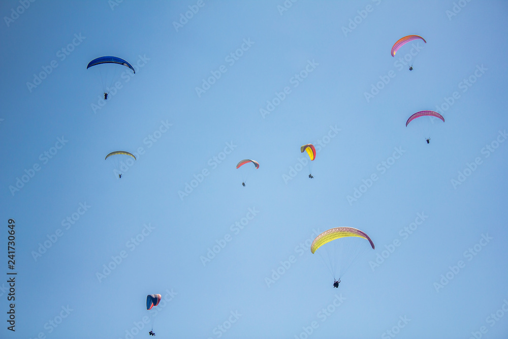 several paragliders on colorful parachutes in a clear blue sky several paragliders on colorful parachutes in a clear blue sky