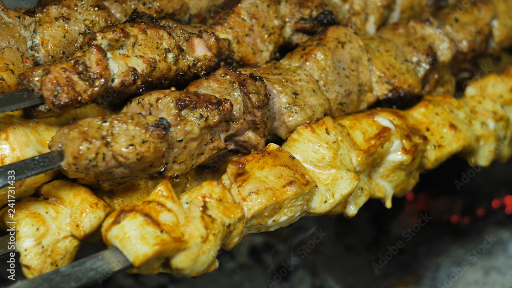 Kebabs of white and red meat strung on a skewer on a grill doused with marinade