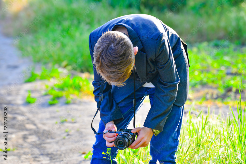 A boy with a camera walks down the street and takes pictures of wild flowers. A boy with a camera walks down the street and takes pictures of wild flowers.