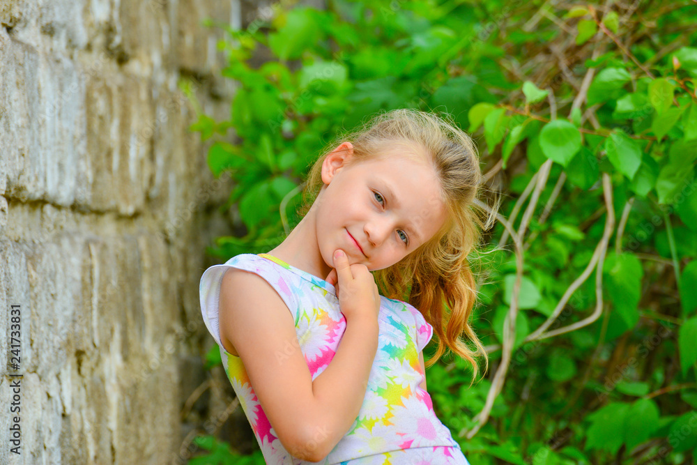 Young and beautiful girl posing against a brick wall on the street with a smile in a summer dress. Young and beautiful girl posing against a brick wall on the street with a smile in a summer dress.