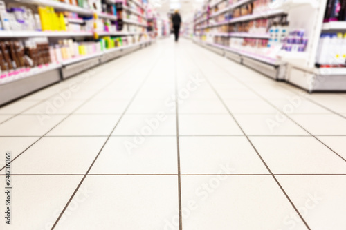 Abstract background blurred photograph of an aisle with shelves in bright modern drugstore at supermarket shopping center © -Marcus-