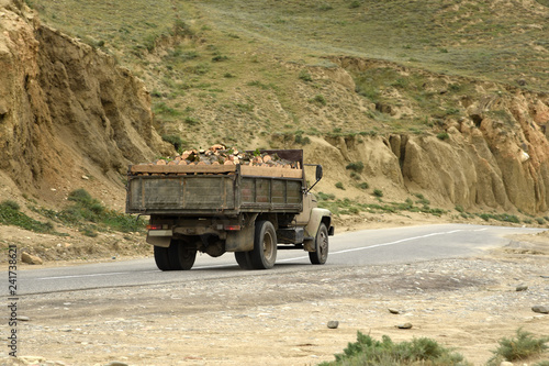 Truck with firewood goes to the mountains on a mountain road