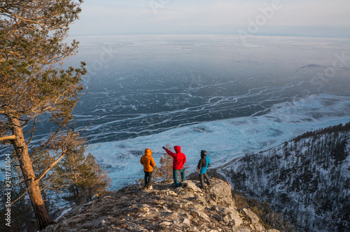 Three people on the rocky edge of Baikal lake shore in Siberia