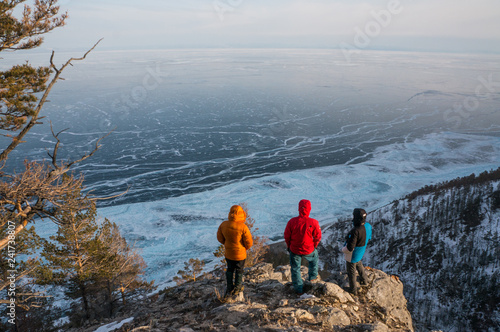 Three people on the rocky edge of Baikal lake shore in Siberia
