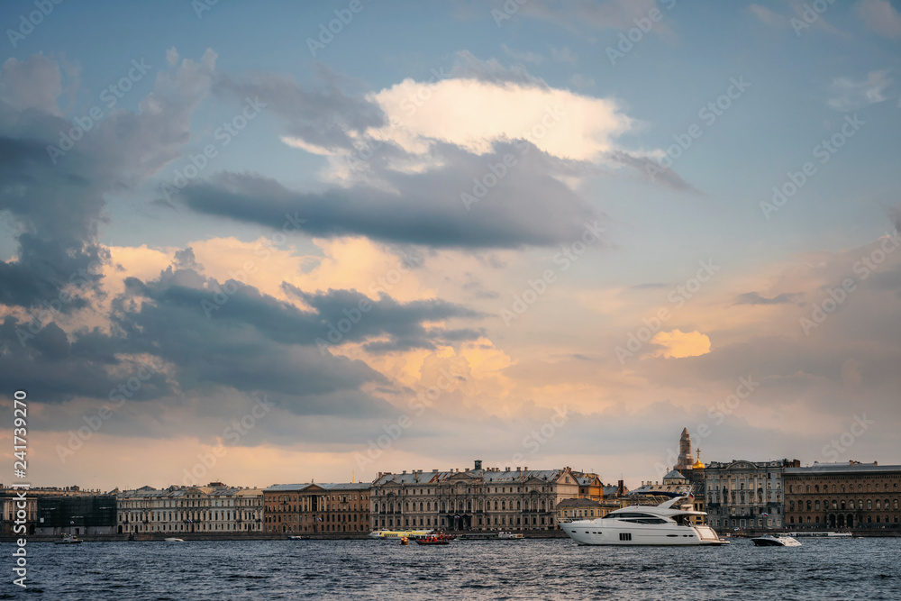 Tourist boats and yachts floats on Neva river on the background of typical architecture and Palace Embankment in the evening at golden sunset, Saint Petersburg, Russia