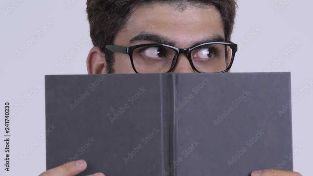 Young Indian hipster man covering face with book Young Indian hipster man covering face with book