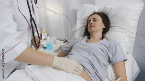 Woman doctor with gloves palpated the abdomen of the patient in the hospital.