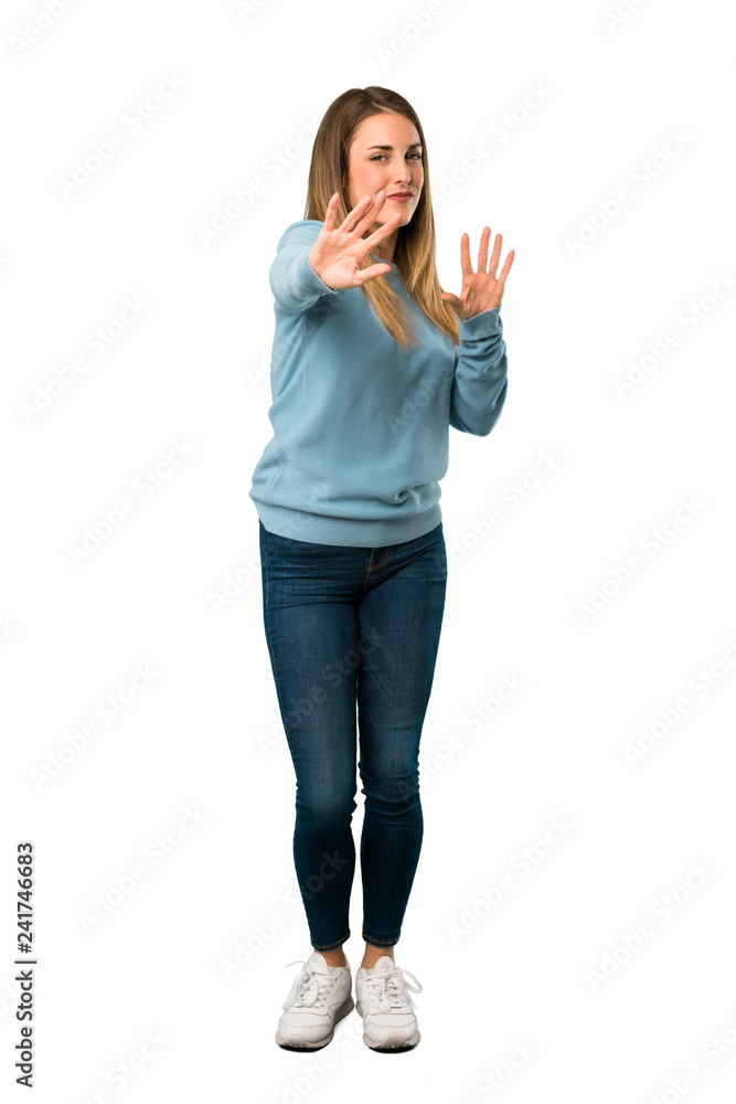 Full body of Blonde woman with blue shirt is a little bit nervous and scared stretching hands to the front on white background Full body of Blonde woman with blue shirt is a little bit nervous and scared stretching hands to the front on white background