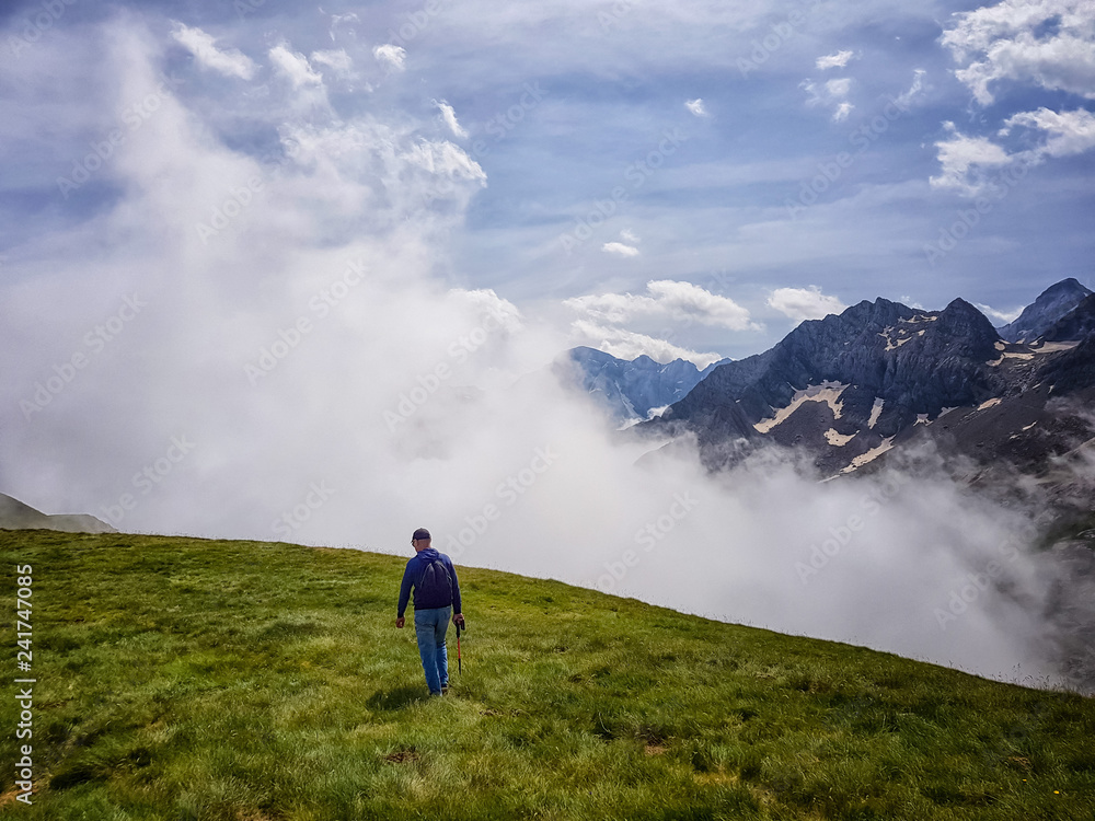 A man with a backpack is on the mountainside against the background of clouds. A man with a backpack is on the mountainside against the background of clouds.