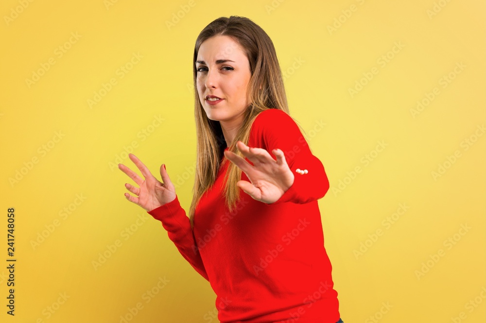Young blonde woman is a little bit nervous and scared on yellow background Young blonde woman is a little bit nervous and scared on yellow background