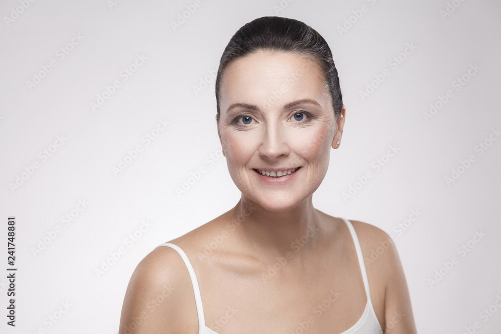 Closeup portrait of charming, pretty, attractive woman with perfect skin smiling after cream, balm, mask, lotion, isolated on grey background. Indoor, studio shot, copy space, advertisement concept Closeup portrait of charming, pretty, attractive woman with perfect skin smiling after cream, balm, mask, lotion, isolated on grey background. Indoor, studio shot, copy space, advertisement concept