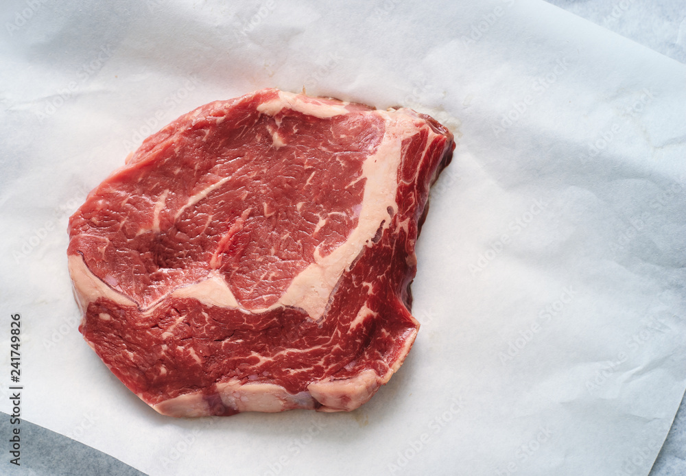 Raw fresh rib-eye steak from marbled beef on white paper