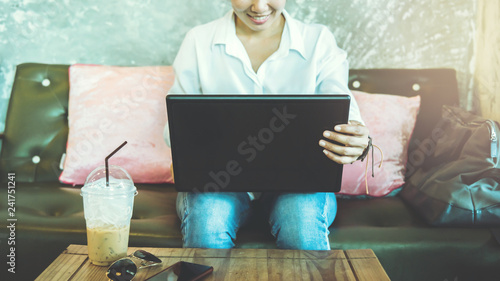 Asian woman sitting relax on the sofa. working with a notebook on the table. in the holiday at a coffee shop.