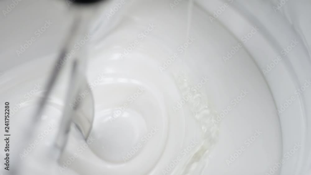 Transparent liquid is added into lab blender to a white cream Transparent liquid is added into lab blender to a white cream
