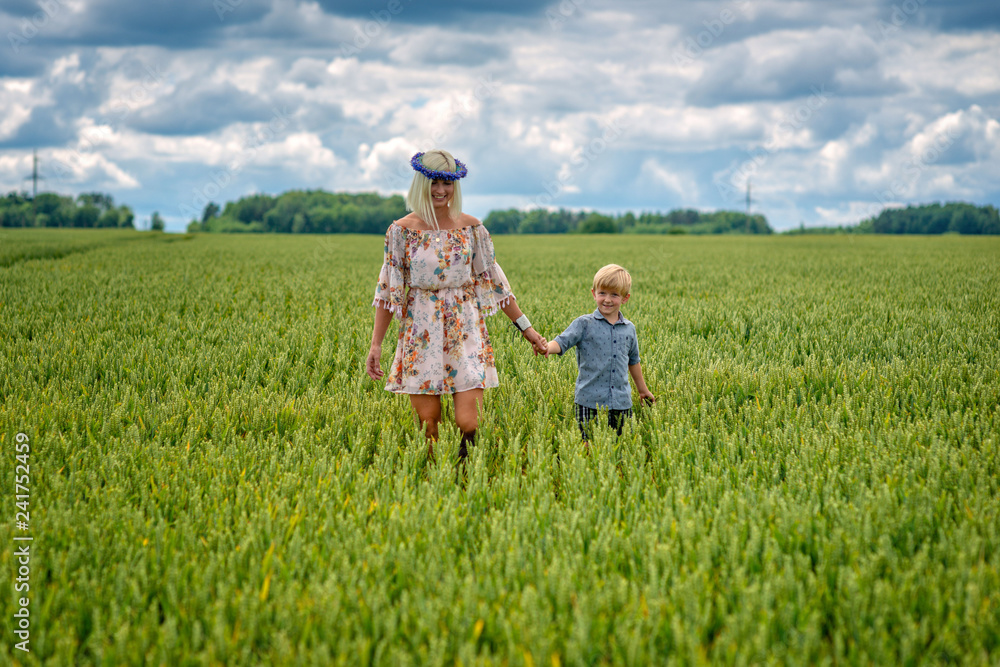 A blonde woman with a child goes through a field of crops.