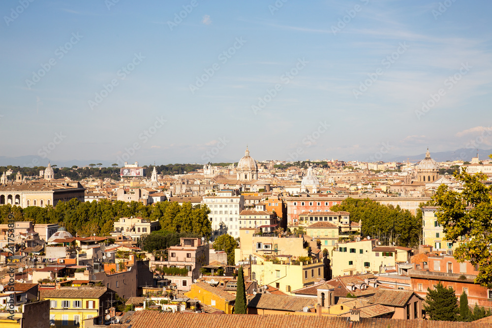 Panoramic view over the old city of Rome beautifully lit by an afternoon sun and set against a blue sky.