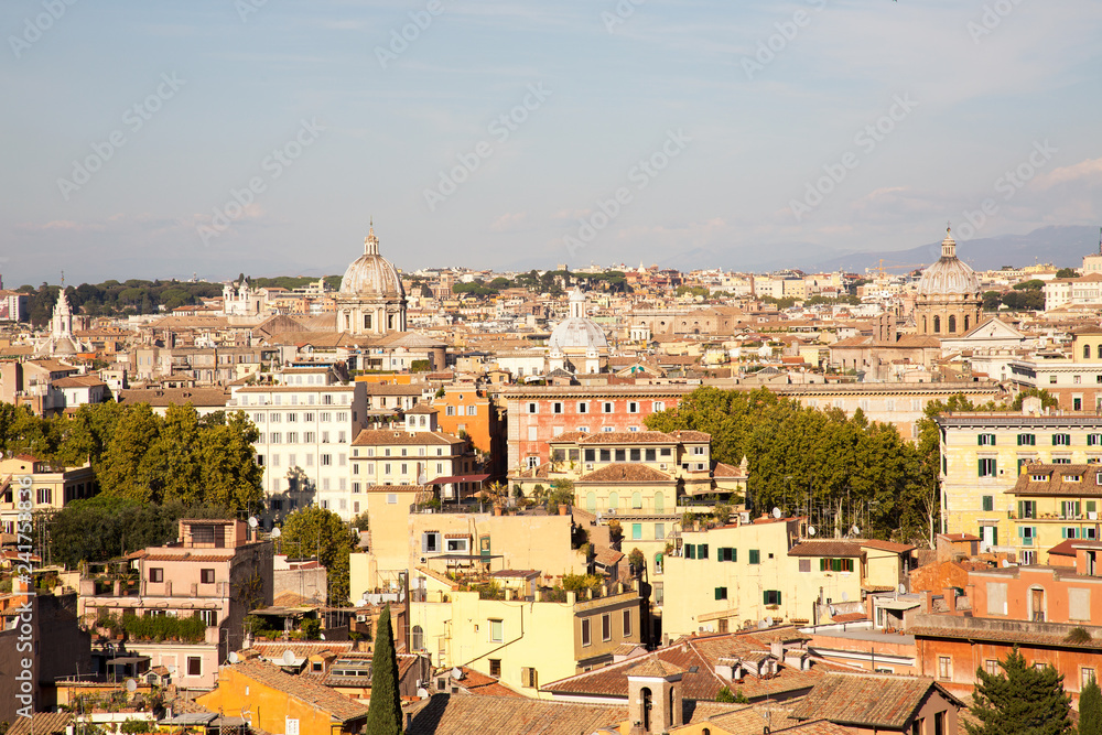 Panoramic view over the old city of Rome beautifully lit by an afternoon sun and set against a blue sky.