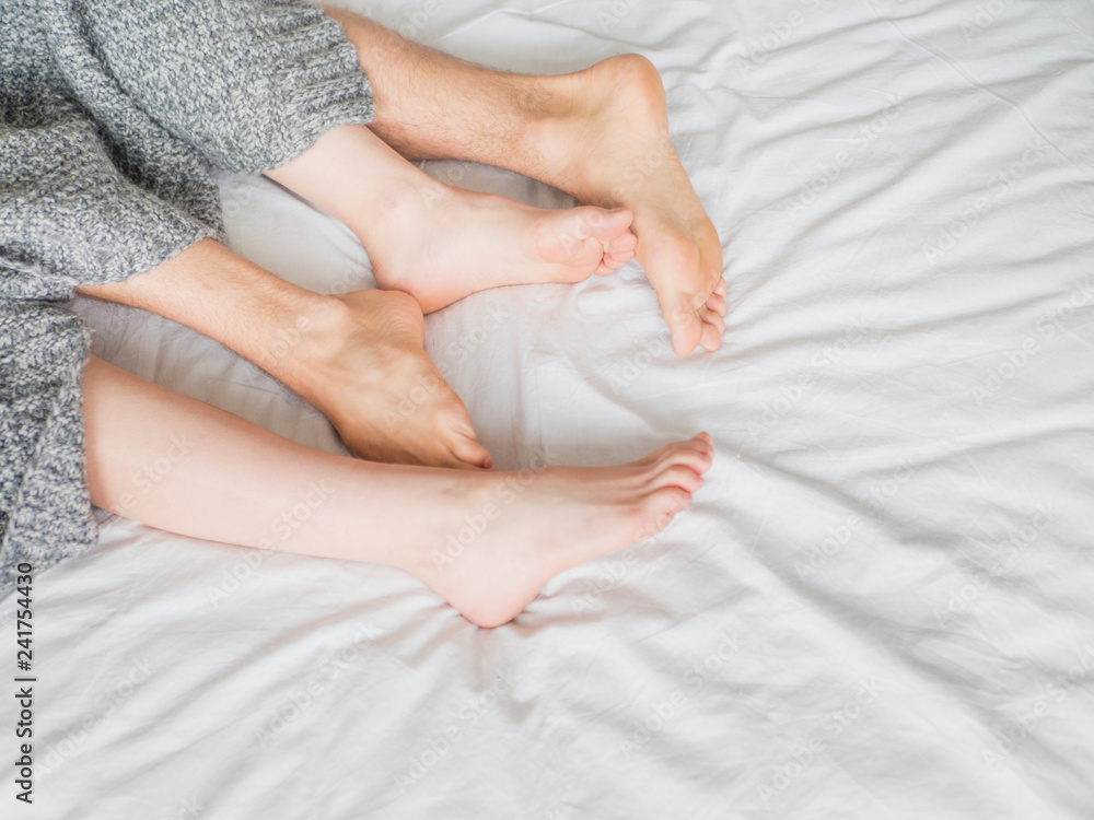 Feet of two couple sleeping on bed under blanket. Love and relationship concept Feet of two couple sleeping on bed under blanket. Love and relationship concept