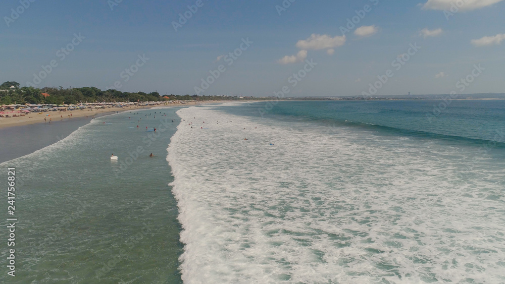 Obraz premium Aerial view sand beach with surfers and tourists, Kuta, Bali. surfers on water surface ocean catch wave. Seascape, beach, ocean, sky sea Travel concept