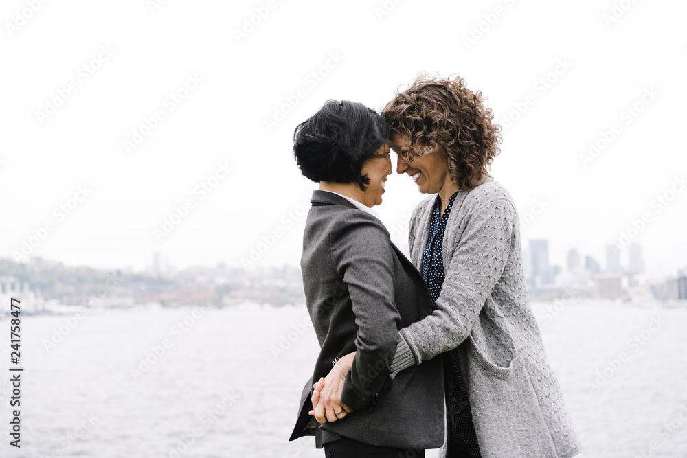 Side view of lesbian couple embracing outdoors Side view of lesbian couple embracing outdoors