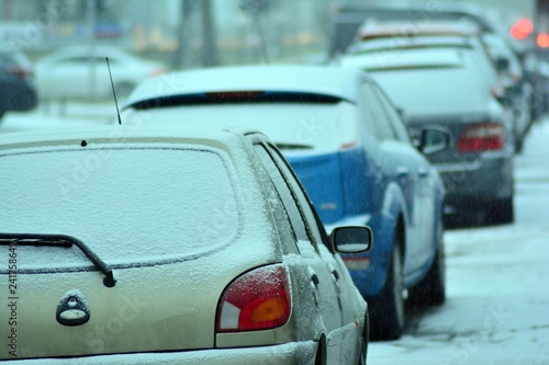 Cars standing in row in traffic jam on city street on slippery snowy road in winter