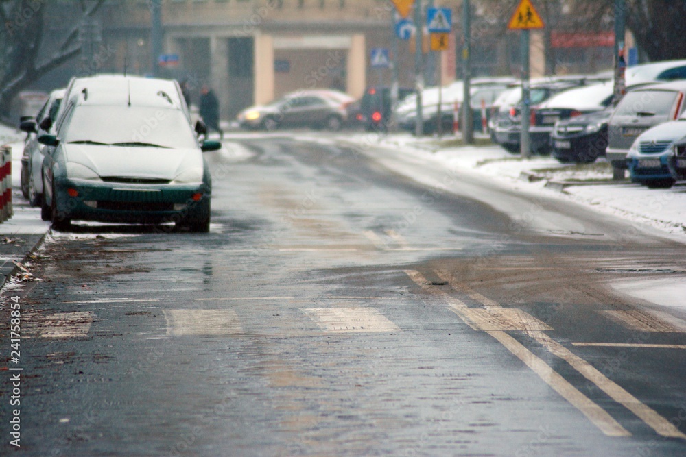 Cars standing in row in traffic jam on city street on slippery snowy road in winter