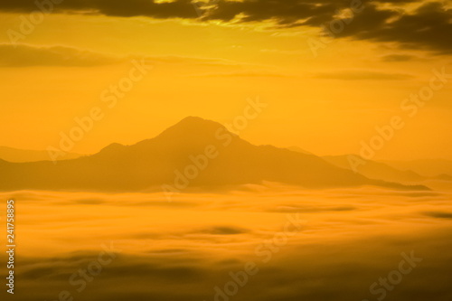 Mountain view misty morning of the hill around with the sea of mist with colorful yellow sun light in the sky background, sunrise at Phu Thok or Phu Tok, Chiang Khan District, Loei, Thailand.