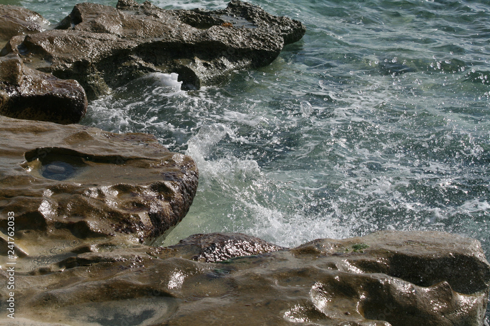 Sea water splashing on the big brown rocks on a beach in Limassol, Cyprus
