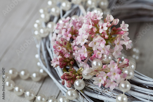 Romantic still life with pastel pink Viburnum flower with pearl necklace