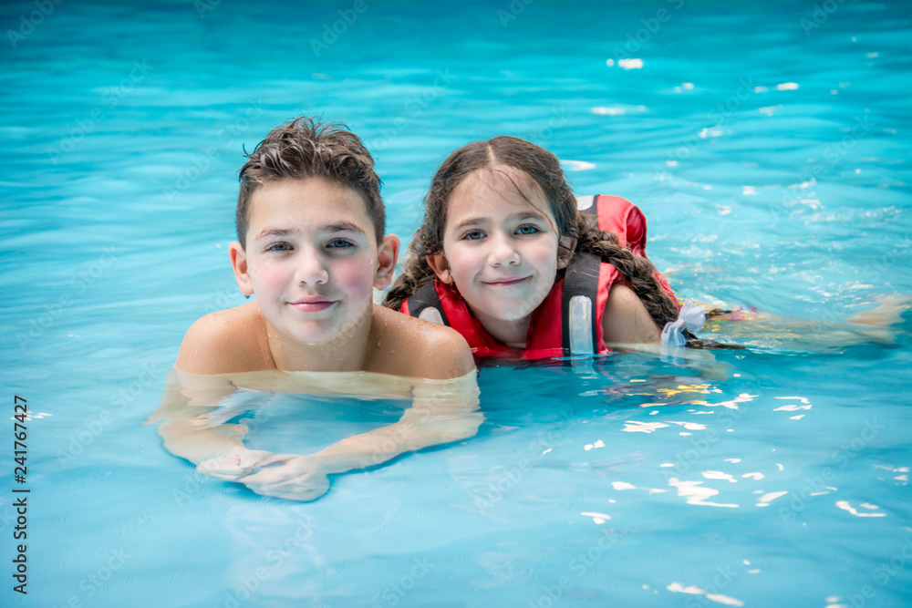 In the water park boy and girl lie in the pool.