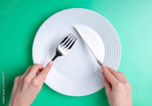 plate fork knife in hand on green background, top view, flat lay