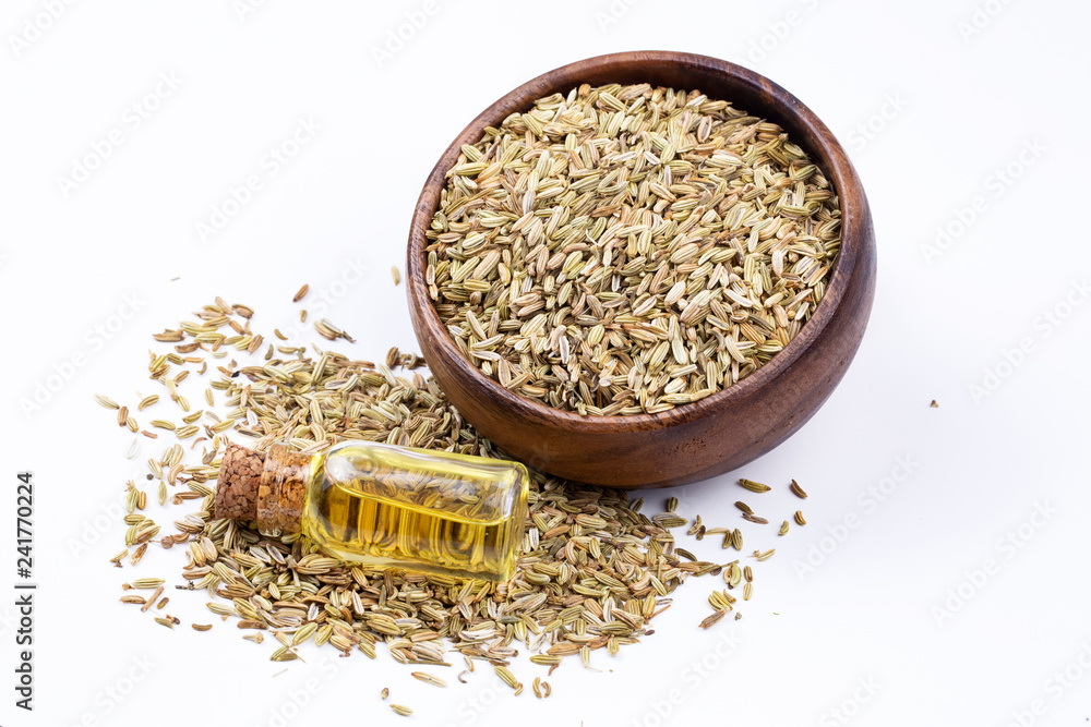 A bottle of fennel essential oil with fresh green fennel twigs and fennel seeds in the background A bottle of fennel essential oil with fresh green fennel twigs and fennel seeds in the background