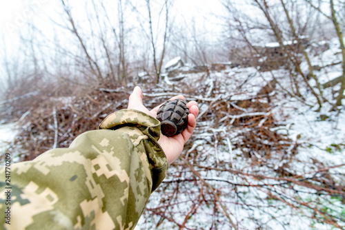 The soldier holds a fragmentation grenade in his hand.