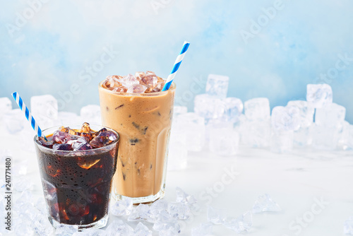 Summer drink iced coffee in a glass and ice coffee with cream in a tall glass surrounded by ice on white marble table over blue background Fototapete