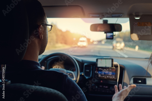 European man is driving the car, while explaining something to his girlfriend. Insight view. © Artem