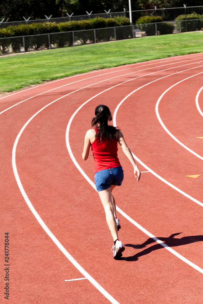 Fototapeta premium Young Woman Running On Track From Back