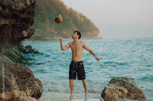a man on a tropical beach throws a coconut. sea, ocean background