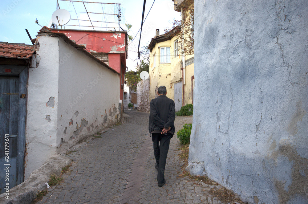 Backside of a walking man on street holding traditional bead