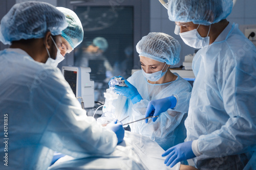 Group of concentrated surgeons engaging in rescue of male patient in operation room at hospital, emergency case, surgery, medical technology, health care and disease treatment concept photo