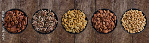 Pekannüsse, Walnüsse, Cashewkerne,Mandelkerne und Erdnüsse in Schüsseln auf Hintergrund aus Holz.