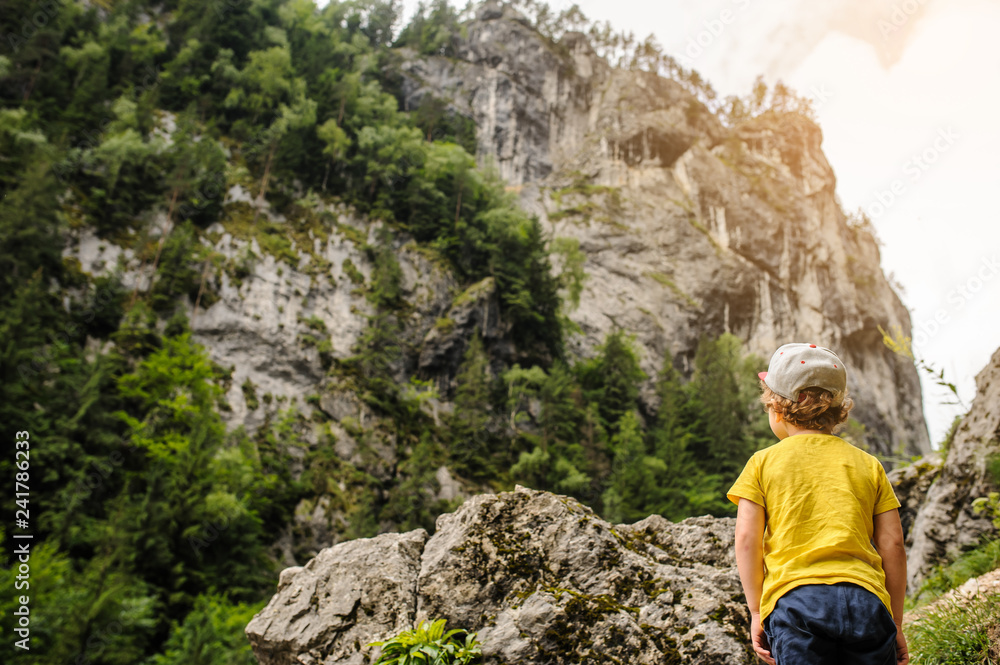 A 6-years blond boy near a rocky mountain