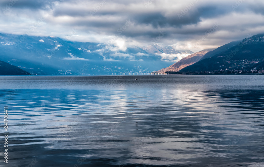 Landscape of Lake Maggiore with cloudy sky and Swiss mountains in background, Luino, Italy