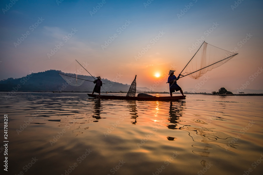 Fisherman on boat river sunset Asia fisherman net using on wooden boat casting net sunset or sunrise in the Mekong river