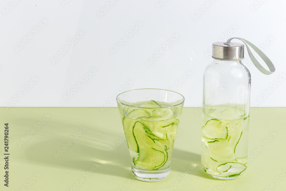 A bottle of cucumber water on a light green background. Minimalistic creative concept. Copy space. A bottle of cucumber water on a light green background. Minimalistic creative concept. Copy space.