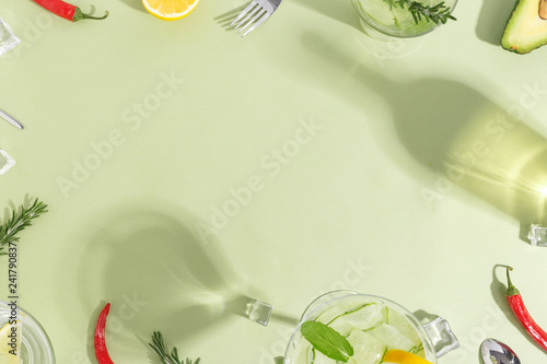 Glass goblet with cucumber water, a bottle and fruit on a light green background. Minimalistic creative concept. Copy space.