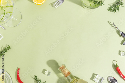 Glass goblet with cucumber water, a bottle and fruit on a light green background. Minimalistic creative concept. Copy space.