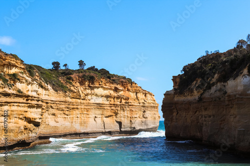 View from inside Loch Ard Gorge without any tourists on a clear summer day with sea breeze, waves and blue sky (Great Ocean Road, Victoria, Australia)