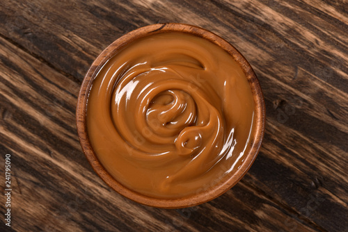 Dulce de leche bowl isolated on wooden background