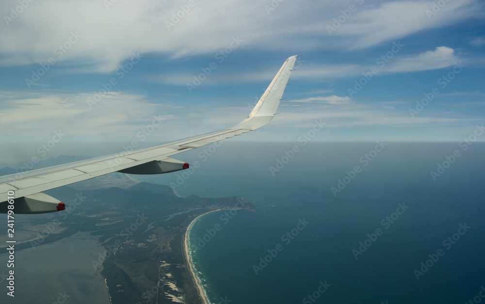 Fototapeta premium Wing of an airplane flying above the beach