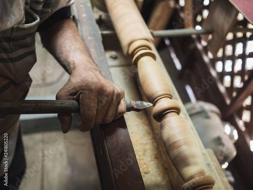 Hands of carpenter turning wood on lathe